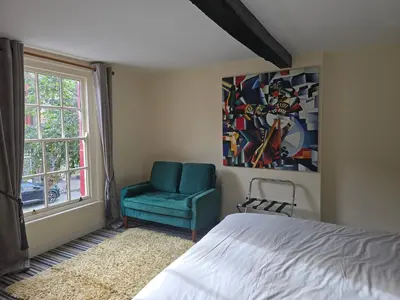 a bedroom with a blue chair and a window at Family room 2 - The Unicorn Hotel in Llanidloes