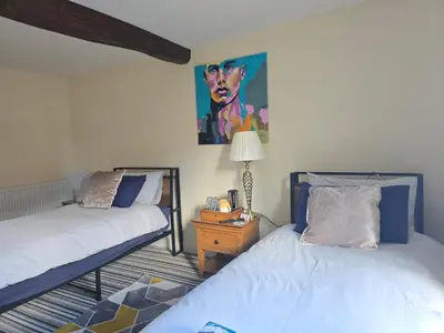 a bedroom with two beds and a painting on the wall at Family room 2 - The Unicorn Hotel in Llanidloes