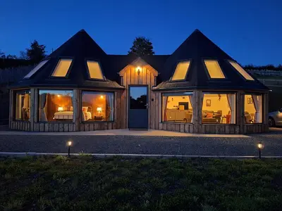 a large house with glass doors and windows at night at Y Cwlwm - The Celtic Knot in Lampeter