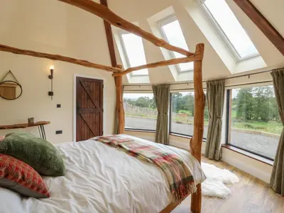 a bedroom with a bed and large windows at Yr Awen - Inspiration in Lampeter