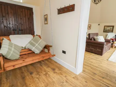 a porch swing in a living room with a couch at Yr Awen - Inspiration in Lampeter