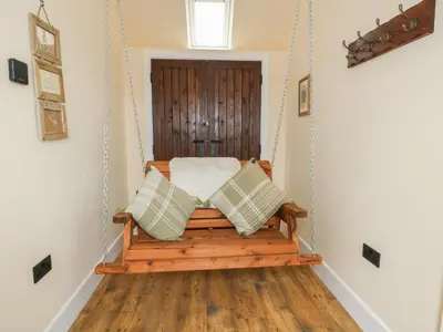 a porch swing with pillows in a room at Yr Awen - Inspiration in Lampeter