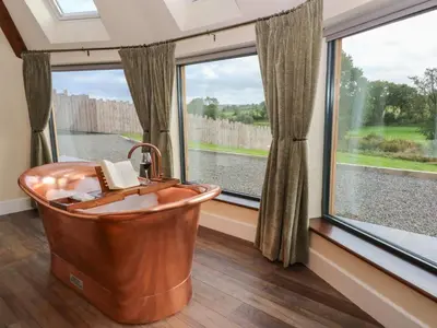 a bath tub in a room with a large window at Ty Crwn - The Roundhouse in Lampeter