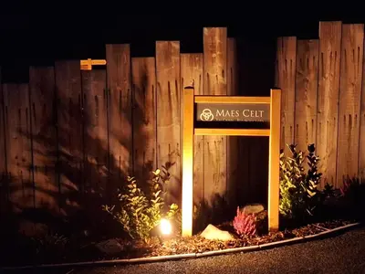 a sign in front of a wooden fence at night at Ty Crwn - The Roundhouse in Lampeter
