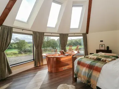 a bedroom with a tub and a large window at Ty Crwn - The Roundhouse in Lampeter