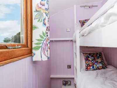 a small bedroom with a bunk bed and a window at Brondel Luxury Shepherd's Hut in Aberystwyth