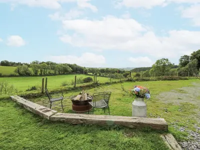 a field with two chairs and a vase of flowers at Brondel Luxury Shepherd's Hut in Aberystwyth