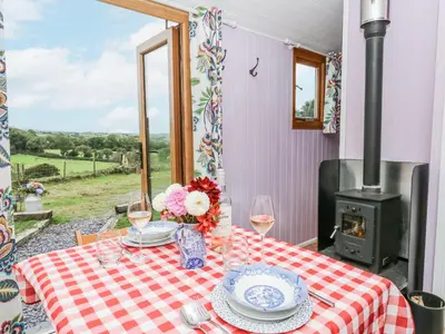 a table with glasses of wine and a stove at Brondel Luxury Shepherd's Hut in Aberystwyth