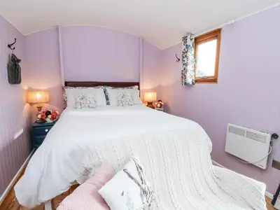 a purple bedroom with a large bed and a window at Brondel Luxury Shepherd's Hut in Aberystwyth