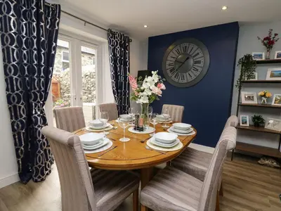 a dining room with a table and a clock on the wall at 6 Upperfield Street in Dolgellau