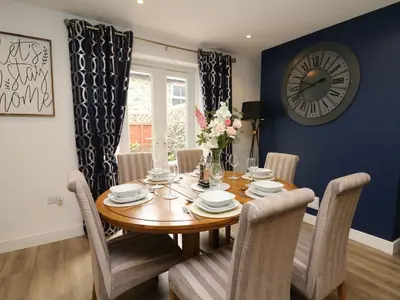 a dining room with a wooden table and a clock on the wall at 6 Upperfield Street in Dolgellau