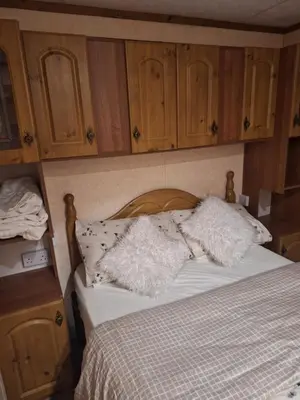 a bedroom with a bed with wooden cabinets at TF1 Static in Aberystwyth