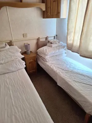 two twin beds in a room with a night stand at TF1 Static in Aberystwyth