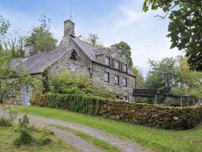 an old stone house with a stone wall at Cynfal Fawr Farmhouse in Ffestiniog