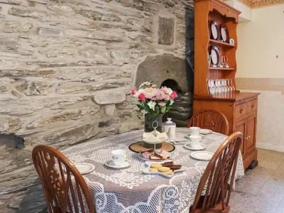 a table with a vase of flowers on it at Cynfal Fawr Farmhouse in Ffestiniog
