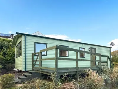 a green tiny house sitting on top of a field at Hafren View in Machynlleth