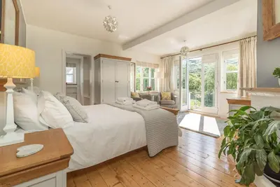 a bedroom with a white bed and a living room at Artro in Llanbedr