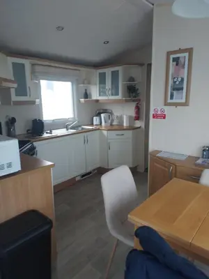 a kitchen with white cabinets and a table and a window at Rosie's Rest in Aberaeron