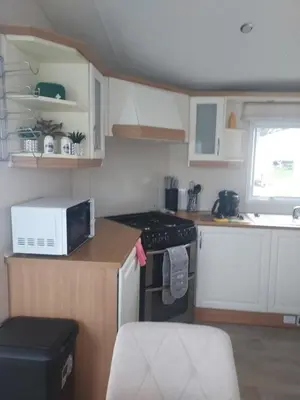 a small kitchen with a stove and a microwave at Rosie's Rest in Aberaeron