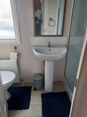 a bathroom with a sink and a mirror and a toilet at Rosie's Rest in Aberaeron
