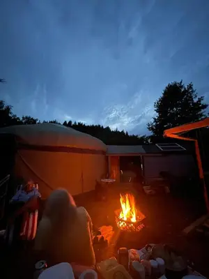 a person laying around a fire in a tent at Hillside Retreats in Machynlleth