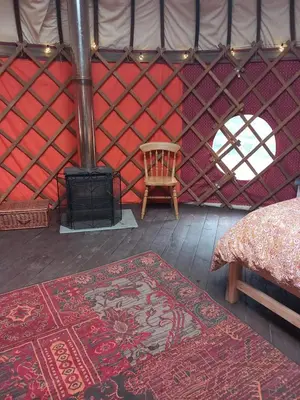 a room with a stove and a rug in a yurt at Hillside Retreats in Machynlleth