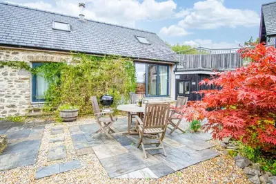 a patio with a table and chairs in a garden at West Barn - 2 Bedroom Cottage - Llandeilo in Llandeilo
