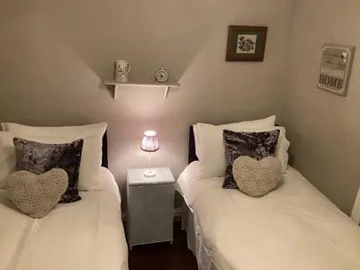 two beds with heart pillows in a bedroom at Patchwork cottage - Grade 2 listed cottage in Snowdonia in Maentwrog