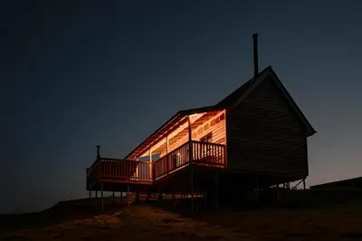 a large wooden house with a deck at night at Woolly Wood Cabins - Nant in Abbey-Cwmhir
