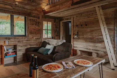 a living room with a couch and a table with pizza at Woolly Wood Cabins - Nant in Abbey-Cwmhir