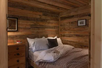 a bedroom with wooden walls and a bed with pillows at Woolly Wood Cabins - Nant in Abbey-Cwmhir