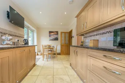 a large kitchen with wooden cabinets and a table at Mehefin in Harlech