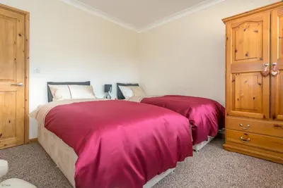 a bedroom with two beds with pink blankets at Mehefin in Harlech