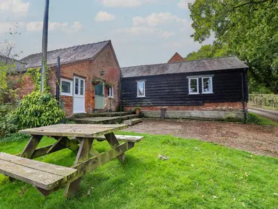 a wooden picnic table in front of a building at Upper Pandy Farm in Welshpool