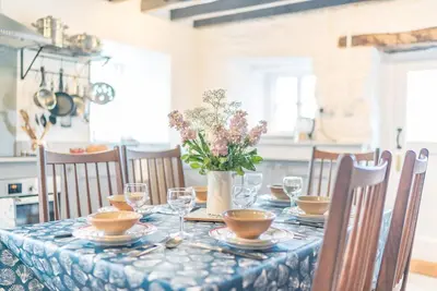 a table with a blue table cloth and a vase of flowers at Pwll-Y-March in Llanbedr