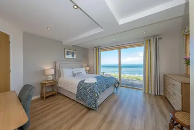 a bedroom with a bed and a view of the ocean at Sarn-Badrig in Harlech