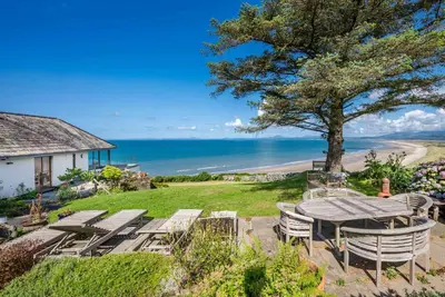 a patio with a table and chairs and the beach at Sarn-Badrig in Harlech