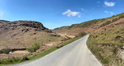 an empty road in the middle of a mountain at Ty Mawr, The Old School Holiday Homes - Pet Friendly in Llanwrtyd Wells