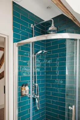 a blue tiled bathroom with a shower with blue tiles at Ty Mawr, The Old School Holiday Homes - Pet Friendly in Llanwrtyd Wells