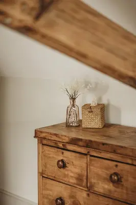 a wooden dresser with a vase of flowers on it at Ty Mawr, The Old School Holiday Homes - Pet Friendly in Llanwrtyd Wells
