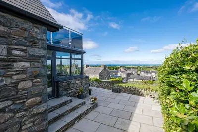 a stone house with glass walls and a patio at Tan-Y-Foel in Dyffryn