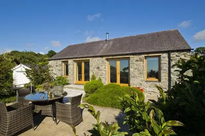 a stone house with a table and chairs in front of it at Hen-Feudy in Dyffryn