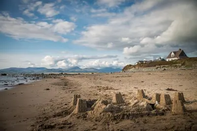 a sand castle on a beach with a house in the background at Maes-Artro-Lodge in Llanbedr