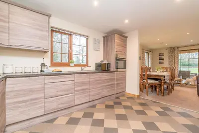 a kitchen with wooden cabinets and a dining room at Maes-Artro-Lodge in Llanbedr