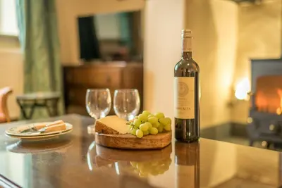 a bottle of wine and wine glasses on a table at Ceseilgwm in Corwen