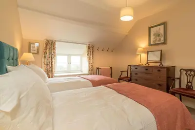 a bedroom with two beds and a dresser and a window at Ceseilgwm in Corwen