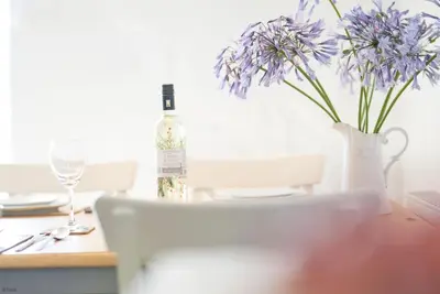 a bottle of wine sitting on a table with a vase of flowers at Ysgubor-Bennar in Dyffryn