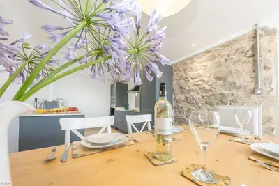 a dining table with a bottle of wine and purple flowers at Ysgubor-Bennar in Dyffryn