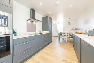 a kitchen with blue cabinets and a dining room at Ysgubor-Bennar in Dyffryn