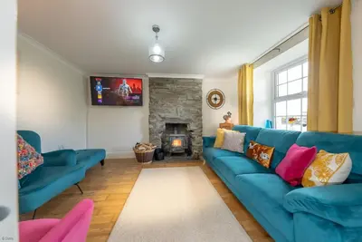 a living room with a blue couch and a fireplace at Isgoed in Talsarnau